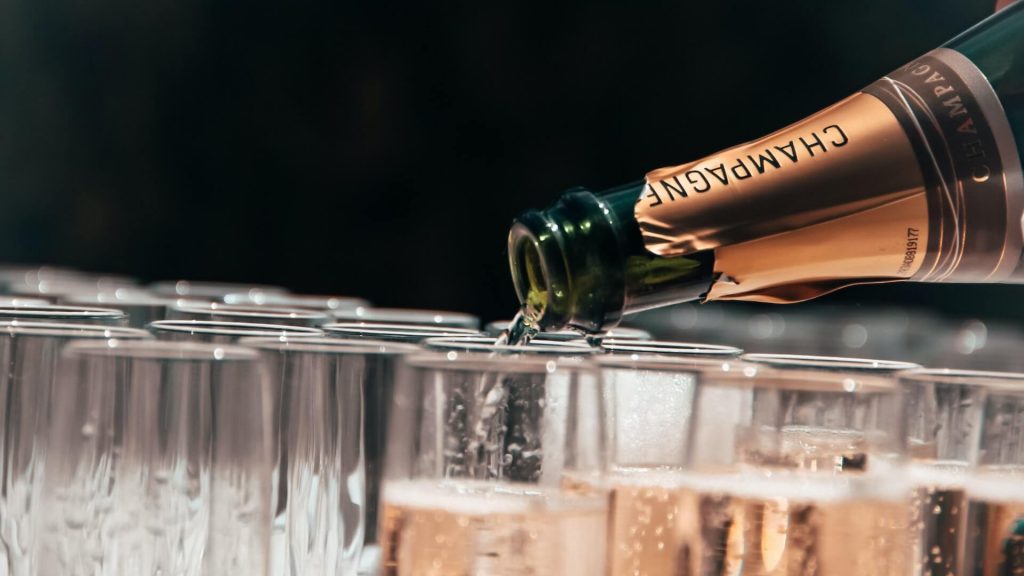 Burbujas subiendo mientras se vierte champán en copas de cristal, una celebración en curso.