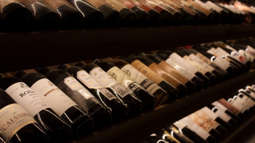 Vista del interior de una bodega bien surtida, que muestra una gran variedad de botellas de vino y almacenamiento.